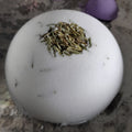 White ball with green material on a textured surface with purple and yellow objects.