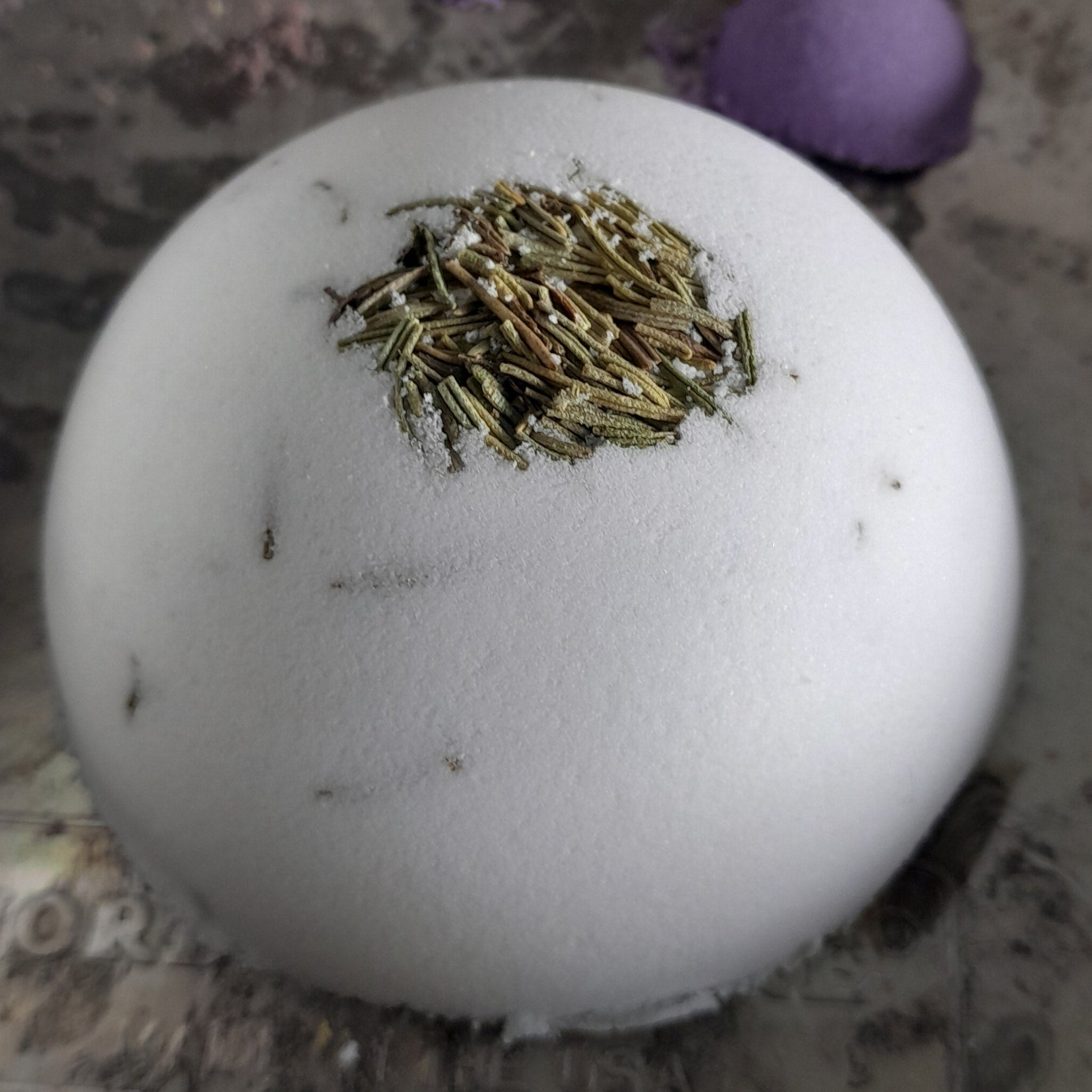 White ball with green material on a textured surface with purple and yellow objects.