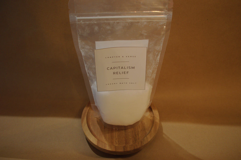 Product packaging labeled 'Capitalism Relief' on a wooden stand with a plain background