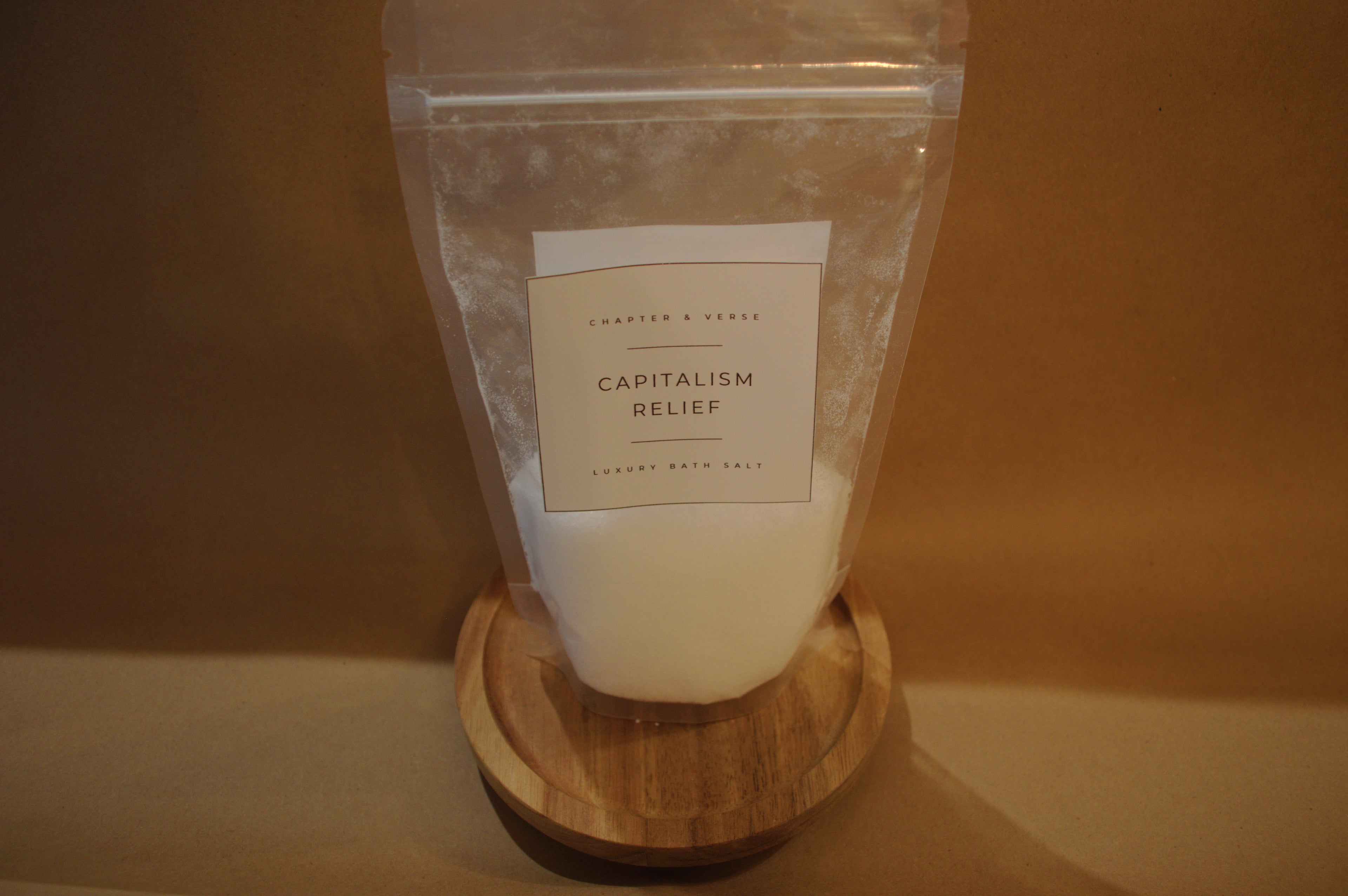 Product packaging labeled 'Capitalism Relief' on a wooden stand with a plain background