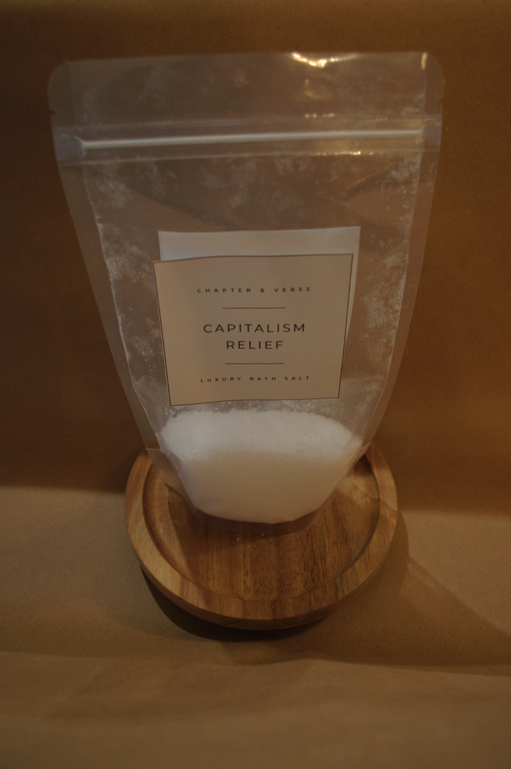 Bag of 'Capitalism Relief' on a wooden coaster with a brown background