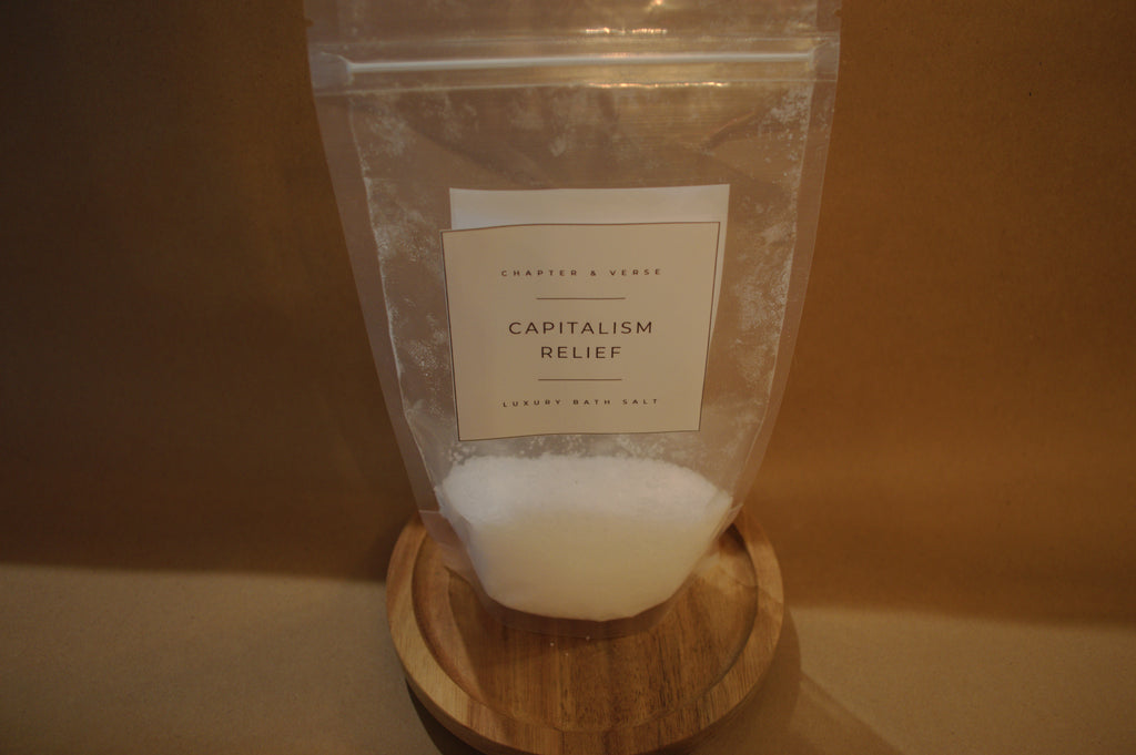 Bag labeled 'Capitalism Relief' on a wooden stand with a plain background