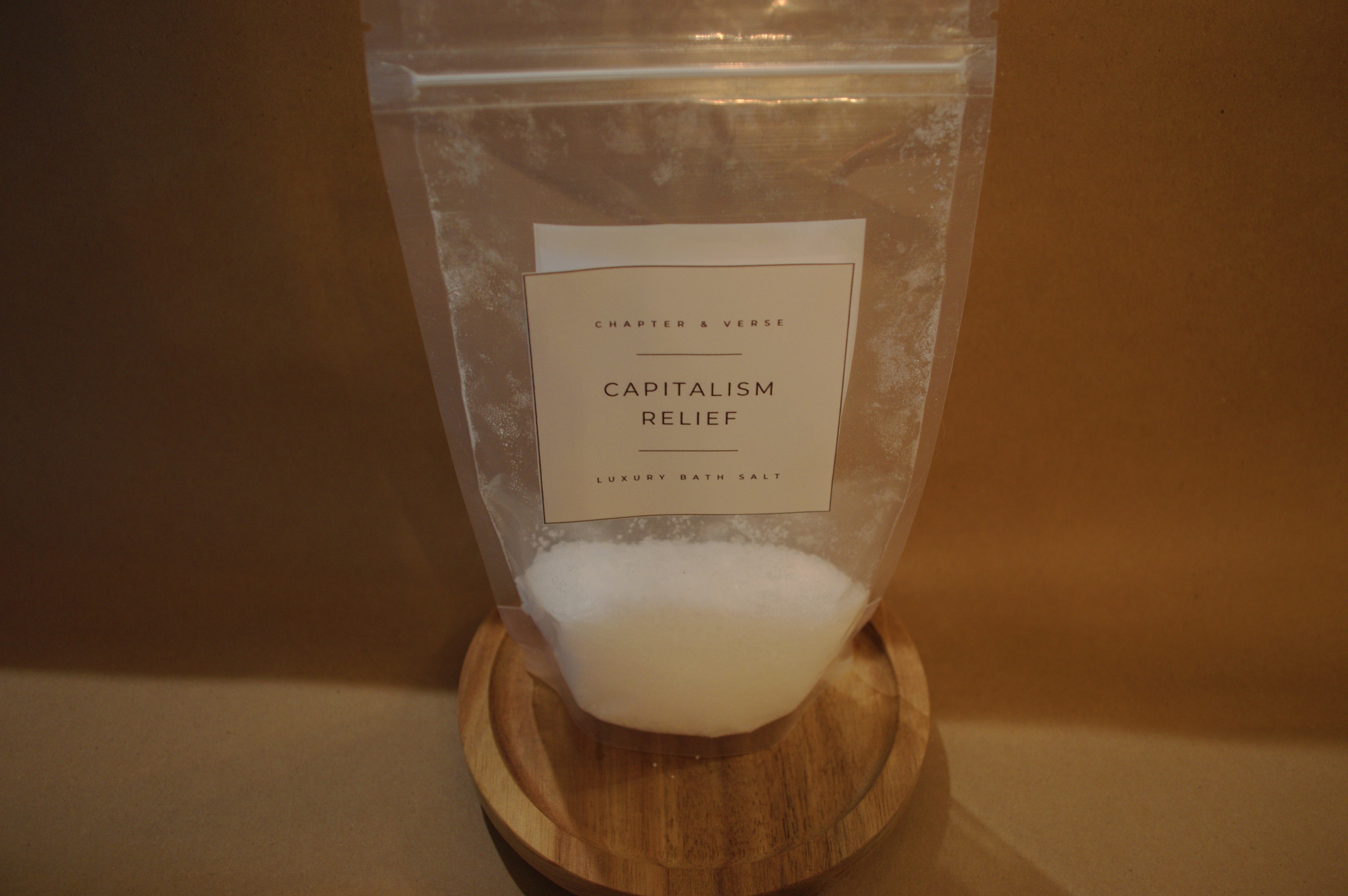 Bag labeled 'Capitalism Relief' on a wooden stand with a plain background
