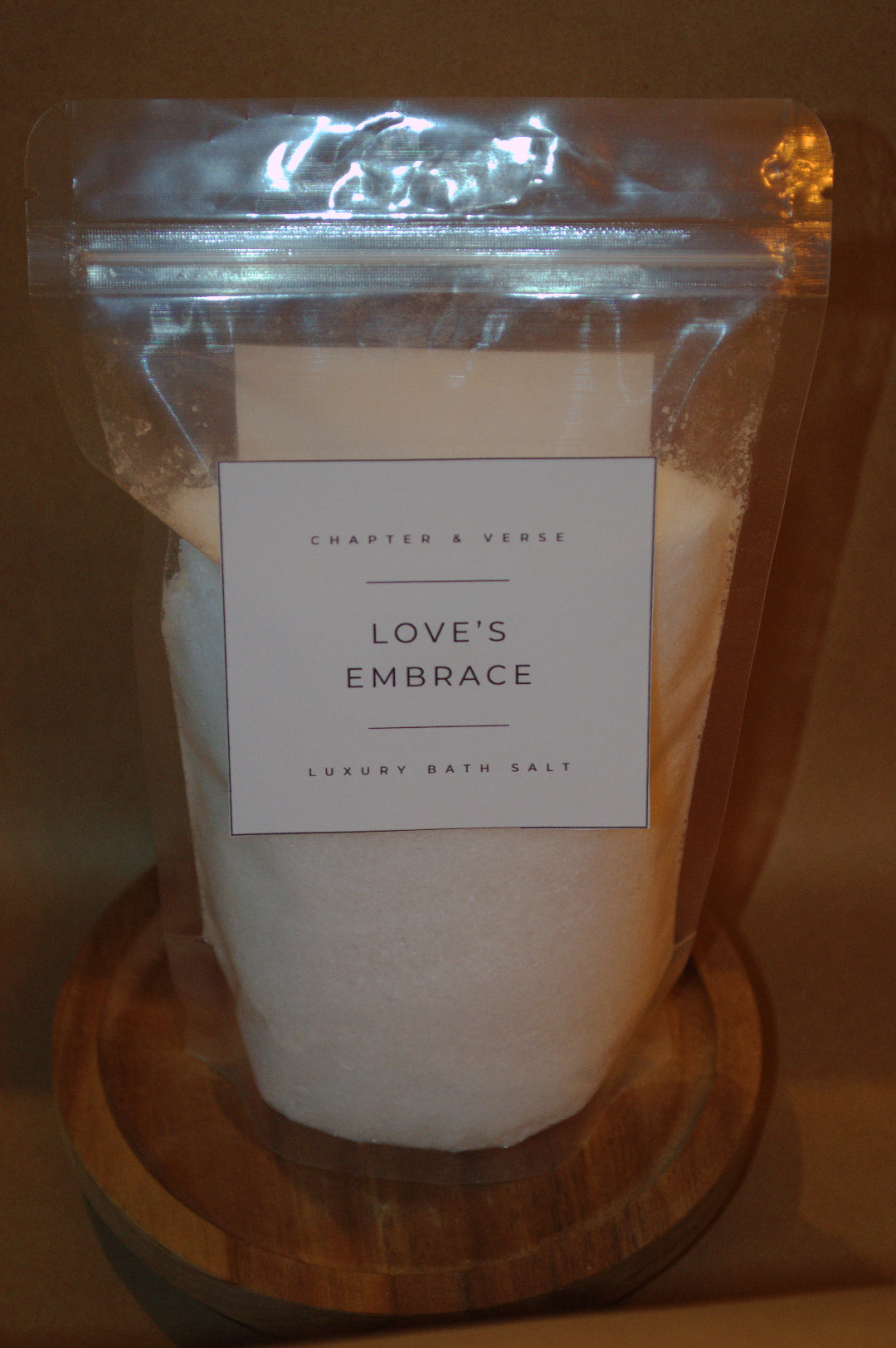 Pack of Chapter & Verse Love's Embrace luxury bath salt on a wooden coaster.