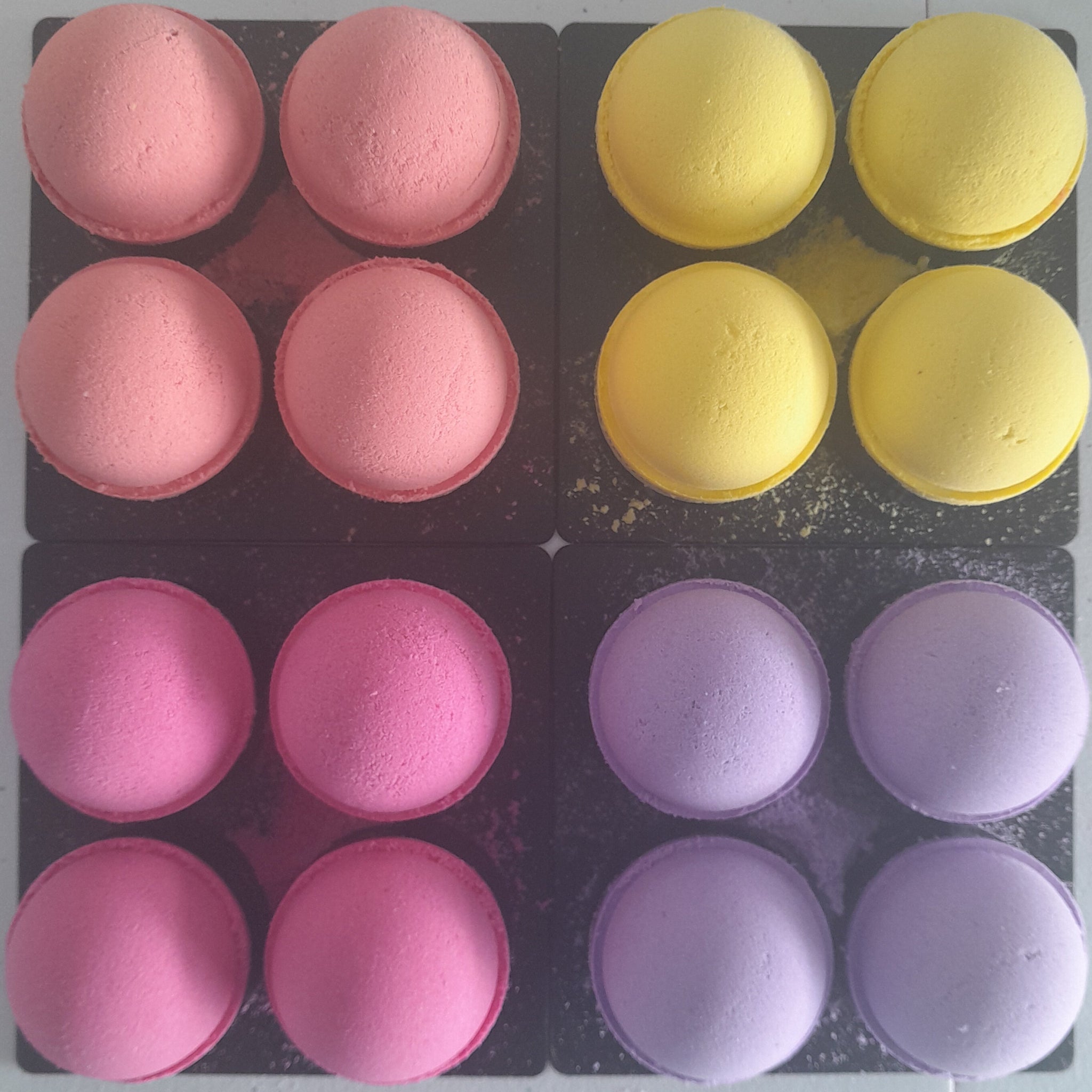Grid of yellow, purple, and pink bath bombs on a gray surface