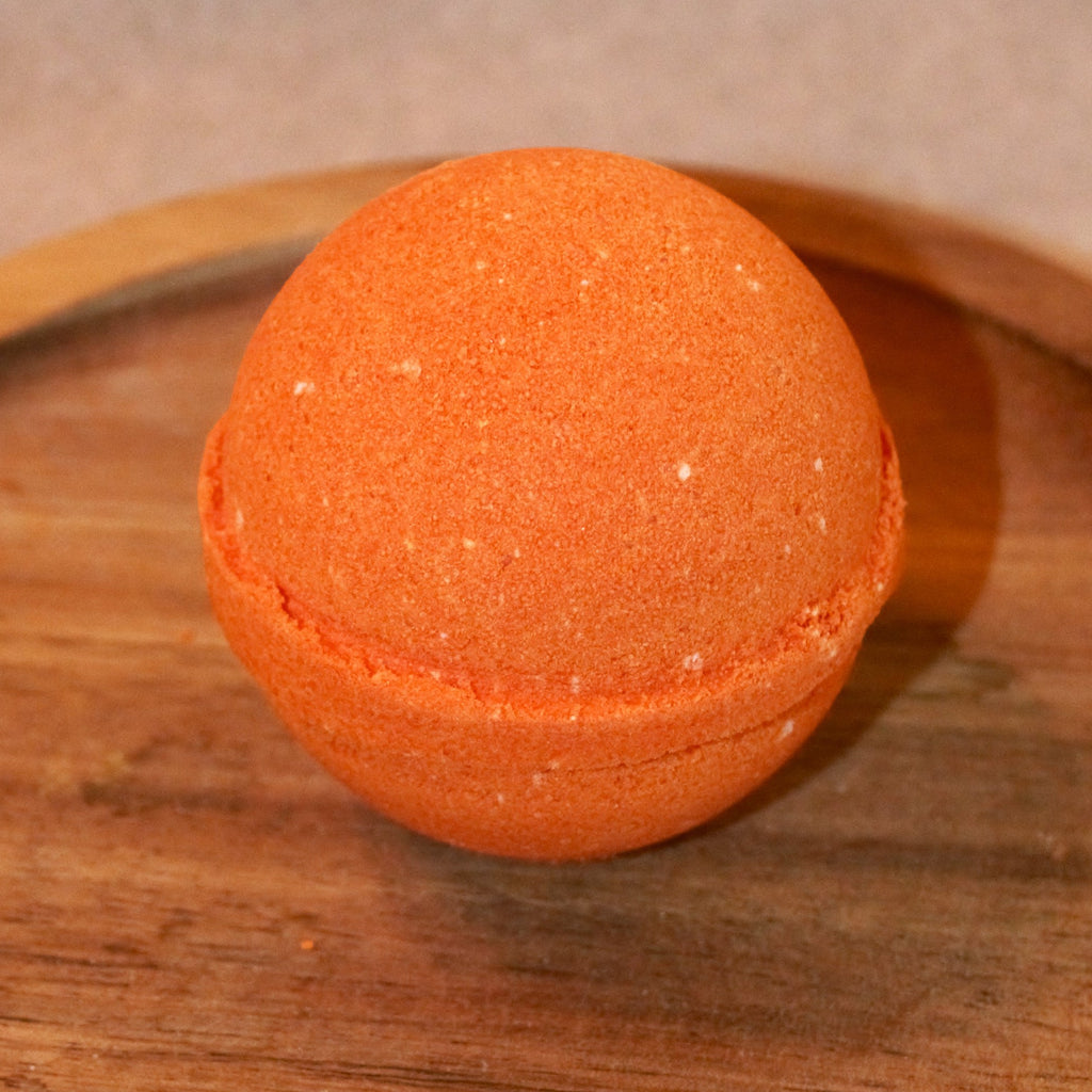 Orange bath bomb on a wooden tray with a neutral background