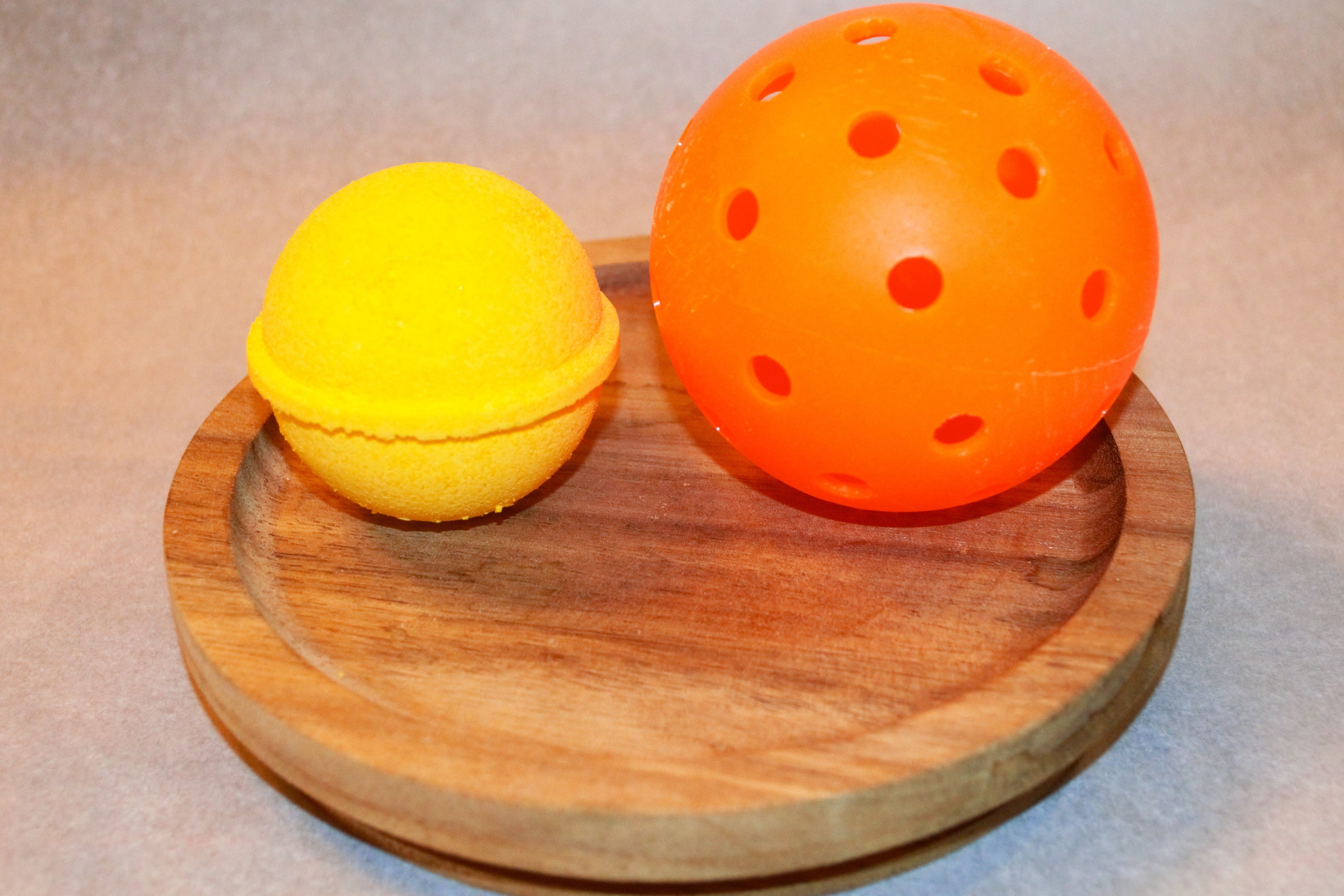 Signature Brazilian Orange and Coconut Bath Bomb size comparison with a pickleball