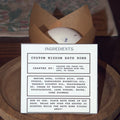 Custom wisdom bath bomb with ingredients label on a wooden surface